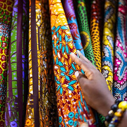 Small business owner of an African Print, Ankara fabric shop proudly displaying different kinds of textile prints.