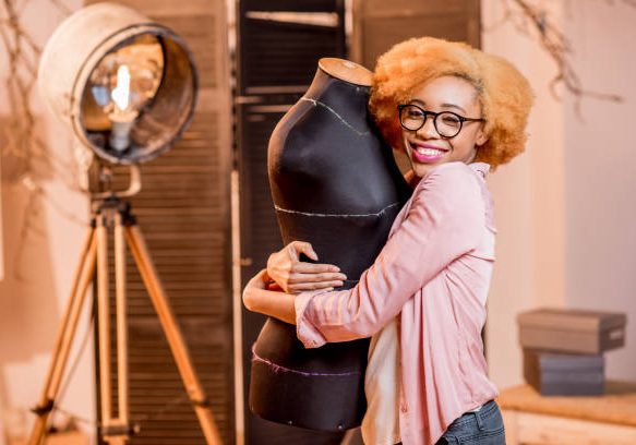 Portrait of a young african fashion designer with mannequin at the tailoring studio