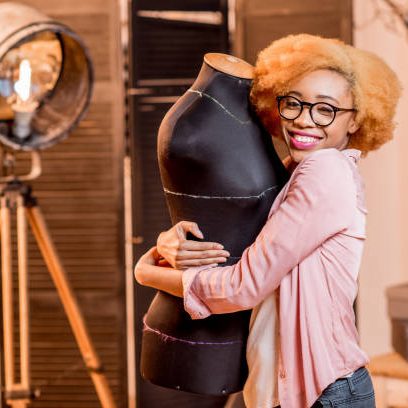 Portrait of a young african fashion designer with mannequin at the tailoring studio